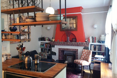 Foto de salón abierto tradicional pequeño con parades naranjas, suelo de madera en tonos medios, todas las chimeneas, marco de chimenea de ladrillo y televisor independiente