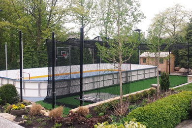 Large contemporary backyard partial sun outdoor sport court in New York with with outdoor playset and natural stone pavers.