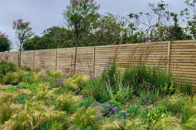 Foto de jardín de secano contemporáneo grande en verano en patio trasero con parterre de flores, exposición total al sol y con madera