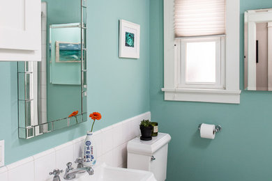 This is an example of a small transitional bathroom in Santa Barbara with white cabinets, a corner tub, a corner shower, a two-piece toilet, white tile, porcelain tile, blue walls, ceramic floors, tile benchtops and a pedestal sink.