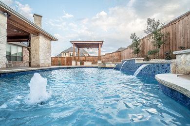 Photo of a large mediterranean backyard custom-shaped natural pool in Dallas with a water feature and stamped concrete.