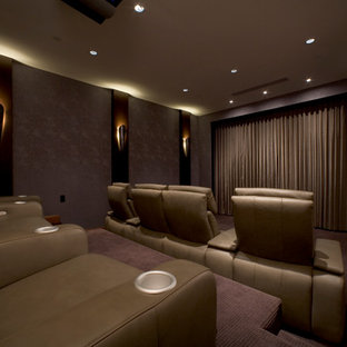 Cette photo montre une grande salle de cinéma tendance fermée avec un mur rose, moquette et un écran de projection.