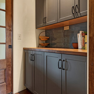 Cette image montre une grande arrière-cuisine linéaire sud-ouest américain avec un placard à porte shaker, des portes de placard grises, un plan de travail en bois, une crédence grise, une crédence en carrelage métro, un sol en carreau de terre cuite, aucun îlot, un sol marron et un plan de travail marron.