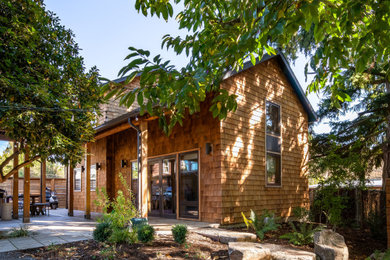Foto de fachada de casa marrón y gris campestre pequeña de dos plantas con revestimiento de madera, tejado a dos aguas, tejado de teja de madera y teja