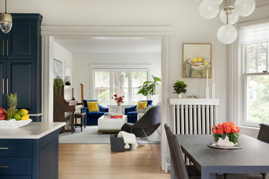 Bild på ett mellanstort vintage vit vitt kök, med luckor med upphöjd panel, blå skåp, bänkskiva i kvarts, vitt stänkskydd, stänkskydd i marmor, rostfria vitvaror, ljust trägolv och en köksö