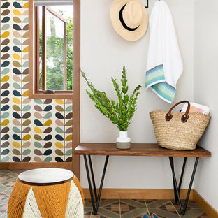 Eklektisk inredning av en entré, med vita väggar och flerfärgat golv