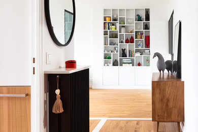 Aménagement d'une entrée moderne de taille moyenne avec un couloir, un mur blanc, parquet clair et un sol marron.