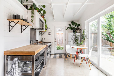Example of a small beach style galley concrete floor and gray floor eat-in kitchen design in Portland with wood countertops, white backsplash, wood backsplash and stainless steel appliances