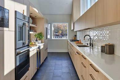Enclosed kitchen - large contemporary galley porcelain tile and black floor enclosed kitchen idea in New York with a double-bowl sink, flat-panel cabinets, light wood cabinets, quartz countertops, white backsplash, subway tile backsplash, black appliances, no island and white countertops