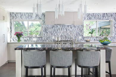 Example of a large trendy galley dark wood floor and brown floor eat-in kitchen design in Denver with flat-panel cabinets, white cabinets, marble countertops, blue backsplash, mosaic tile backsplash, stainless steel appliances, an island and black countertops