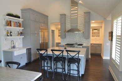 Inspiration for a large transitional dark wood floor and brown floor open concept kitchen remodel in Chicago with an undermount sink, recessed-panel cabinets, gray cabinets, white backsplash, ceramic backsplash, stainless steel appliances and an island