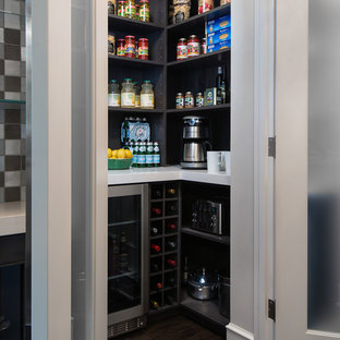 Réalisation d'une arrière-cuisine design en L de taille moyenne avec un plan de travail en quartz modifié, un électroménager en acier inoxydable, un sol en bois foncé, un îlot central, un placard à porte plane, des portes de placard en bois sombre, un sol marron et un plan de travail blanc.