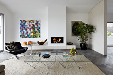 Design ideas for a mid-sized contemporary open concept living room in Melbourne with white walls, dark hardwood floors, a standard fireplace, a plaster fireplace surround and grey floor.