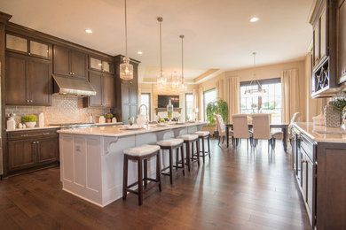 Eat-in kitchen - large traditional u-shaped dark wood floor and brown floor eat-in kitchen idea in Milwaukee with an undermount sink, shaker cabinets, dark wood cabinets, granite countertops, gray backsplash, stainless steel appliances, an island, ceramic backsplash and beige countertops
