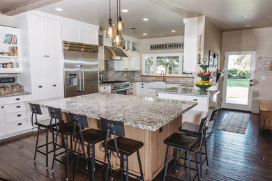 Eat-in kitchen - large farmhouse u-shaped dark wood floor eat-in kitchen idea in Boston with a farmhouse sink, white cabinets, granite countertops, stainless steel appliances, an island, shaker cabinets, brown backsplash and matchstick tile backsplash