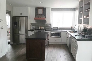 Example of a mid-sized arts and crafts u-shaped porcelain tile and brown floor kitchen design in Los Angeles with an undermount sink, shaker cabinets, white cabinets, granite countertops, gray backsplash, ceramic backsplash, stainless steel appliances and an island