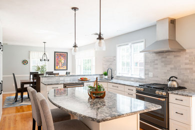 Example of a large transitional l-shaped medium tone wood floor and brown floor eat-in kitchen design in Boston with an undermount sink, shaker cabinets, white cabinets, granite countertops, gray backsplash, subway tile backsplash, stainless steel appliances, an island and gray countertops