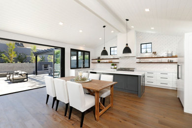 Inspiration for a modern light wood floor open concept kitchen remodel in Orange County with an undermount sink, white cabinets, quartz countertops, white backsplash, subway tile backsplash, an island and white countertops