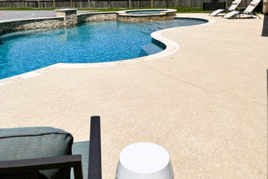Custom shaped swimming pool in Houston with concrete slabs.