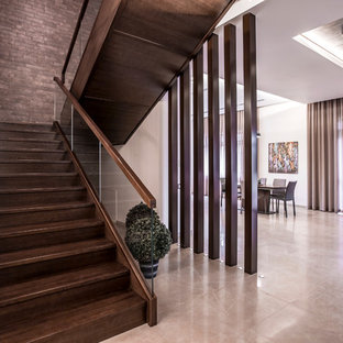 На фото: большие п-образные лестницы в современном стиле с деревянными ступенями, деревянными подступенками и стеклянными перилами