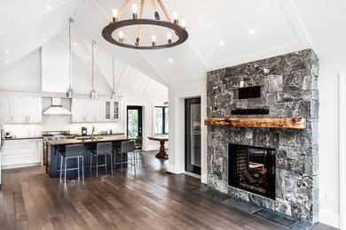 Inspiration for a mid-sized rustic open concept dark wood floor family room remodel in Other with white walls, a standard fireplace, a stone fireplace and a wall-mounted tv