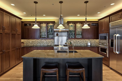 Eat-in kitchen - mid-sized transitional u-shaped light wood floor eat-in kitchen idea in Omaha with an undermount sink, recessed-panel cabinets, dark wood cabinets, marble countertops, beige backsplash, ceramic backsplash, paneled appliances and an island