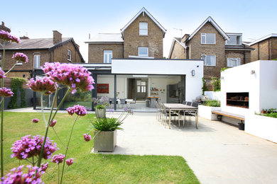 This is an example of a contemporary backyard patio in London with no cover and with fireplace.