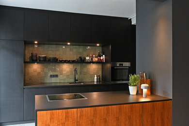 Esempio di un cucina con isola centrale contemporaneo con lavello da incasso, ante lisce, ante nere, top in granito, paraspruzzi verde, paraspruzzi con piastrelle a mosaico e top nero