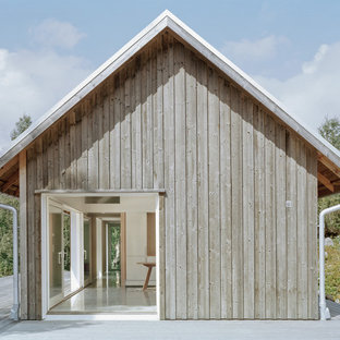 Cette image montre une façade en bois grise nordique de taille moyenne et de plain-pied avec un toit à croupette.