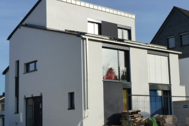 Großes, Zweistöckiges Modernes Einfamilienhaus mit Putzfassade, weißer Fassadenfarbe, Pultdach und Ziegeldach in Köln
