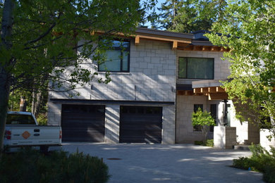 Inspiration for a large contemporary gray two-story stone house exterior remodel in Vancouver with a hip roof