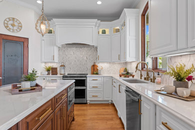 Example of a large classic l-shaped light wood floor and brown floor enclosed kitchen design in Milwaukee with an undermount sink, raised-panel cabinets, white cabinets, quartz countertops, white backsplash, marble backsplash, stainless steel appliances, an island and white countertops