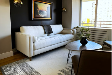 Example of a mid-sized trendy open concept light wood floor and brown floor living room design in New York with black walls
