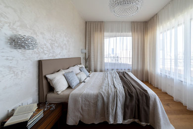 Kleines Modernes Hauptschlafzimmer mit beiger Wandfarbe, braunem Holzboden und braunem Boden in Sonstige