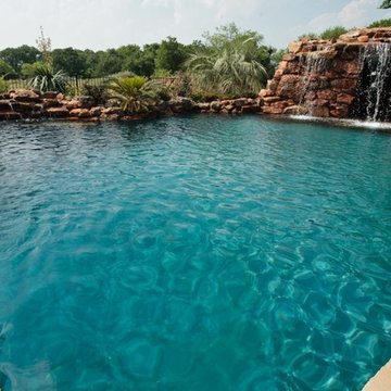 Lagoon style swimming pool with waterfall grotto with spa inside.