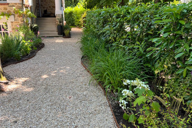 Réalisation d'un jardin champêtre avec une terrasse en bois et une clôture en métal.