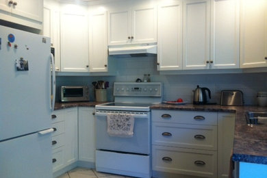 Eat-in kitchen - traditional u-shaped eat-in kitchen idea in Vancouver with a double-bowl sink, shaker cabinets, white cabinets, laminate countertops, white backsplash, ceramic backsplash and white appliances