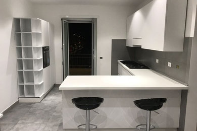 Esempio di una cucina minimalista con lavello da incasso, ante a filo, ante bianche, top in laminato, paraspruzzi a effetto metallico e elettrodomestici neri
