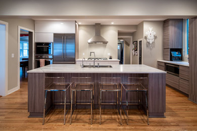Mid-sized trendy l-shaped light wood floor kitchen pantry photo in Minneapolis with a drop-in sink, flat-panel cabinets, gray cabinets, marble countertops, white backsplash, subway tile backsplash, stainless steel appliances and an island