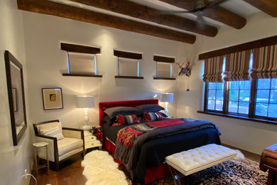 他の地域にある中くらいなサンタフェスタイルのおしゃれな客用寝室 (白い壁、濃色無垢フローリング、茶色い床、表し梁)