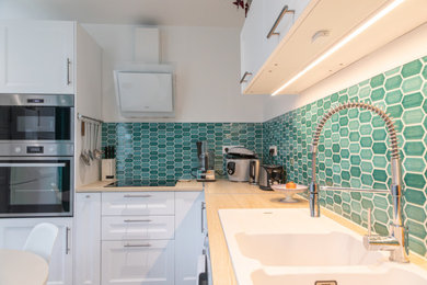 Medium sized contemporary l-shaped enclosed kitchen in Le Havre with a submerged sink, beaded cabinets, white cabinets, laminate countertops, green splashback, ceramic splashback, integrated appliances, ceramic flooring, no island, grey floors and beige worktops.