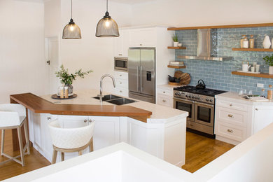 Inspiration for a large scandinavian kitchen in Brisbane with a double-bowl sink, shaker cabinets, white cabinets, quartz benchtops, blue splashback, subway tile splashback, stainless steel appliances, light hardwood floors and with island.