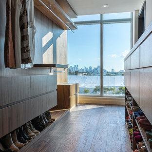 Esempio di una cabina armadio unisex minimal con ante lisce, ante in legno bruno e parquet scuro