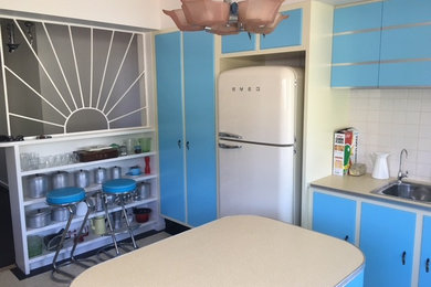Inspiration for a mid-sized midcentury u-shaped separate kitchen in Melbourne with raised-panel cabinets, blue cabinets, laminate benchtops, white splashback, ceramic splashback, with island, a drop-in sink, coloured appliances and linoleum floors.