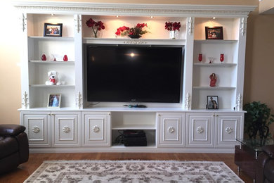 Example of a mid-sized classic enclosed medium tone wood floor and brown floor family room design in New York with beige walls, no fireplace and a media wall