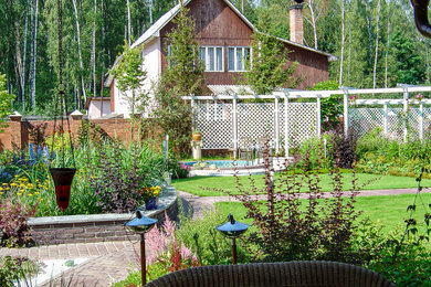 Modelo de jardín tradicional pequeño en verano en patio delantero con parterre de flores, exposición total al sol y adoquines de hormigón