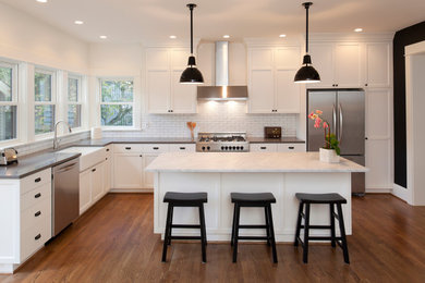 Example of a large transitional l-shaped medium tone wood floor and brown floor open concept kitchen design in San Francisco with a farmhouse sink, shaker cabinets, white cabinets, marble countertops, white backsplash, subway tile backsplash, stainless steel appliances and an island