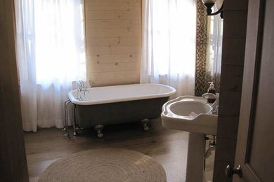 Mid-sized mid-century modern master light wood floor claw-foot bathtub photo in New York with a pedestal sink and brown walls