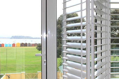 Natural timber plantation shutters and shaped tracked vertical blinds