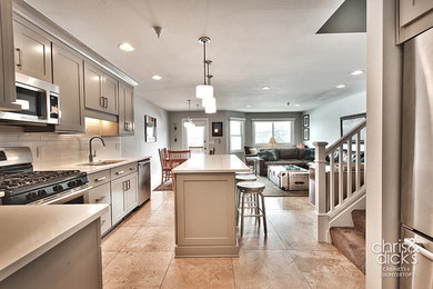Mid-sized minimalist l-shaped travertine floor open concept kitchen photo in Salt Lake City with an undermount sink, recessed-panel cabinets, beige cabinets, quartz countertops, white backsplash, subway tile backsplash, stainless steel appliances and an island